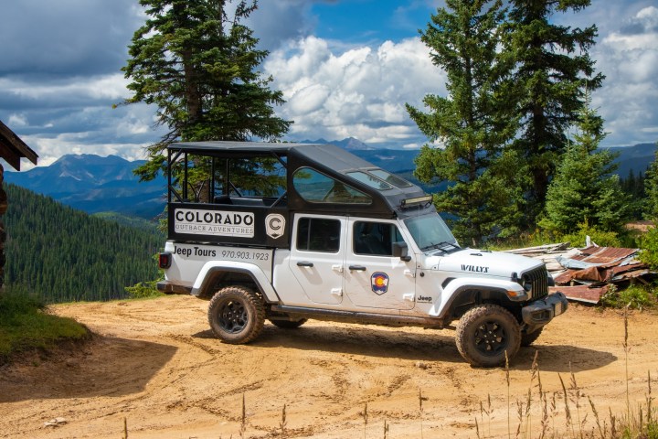 A gladiator Jeep is parked on a forest road in front of a beautiful vista