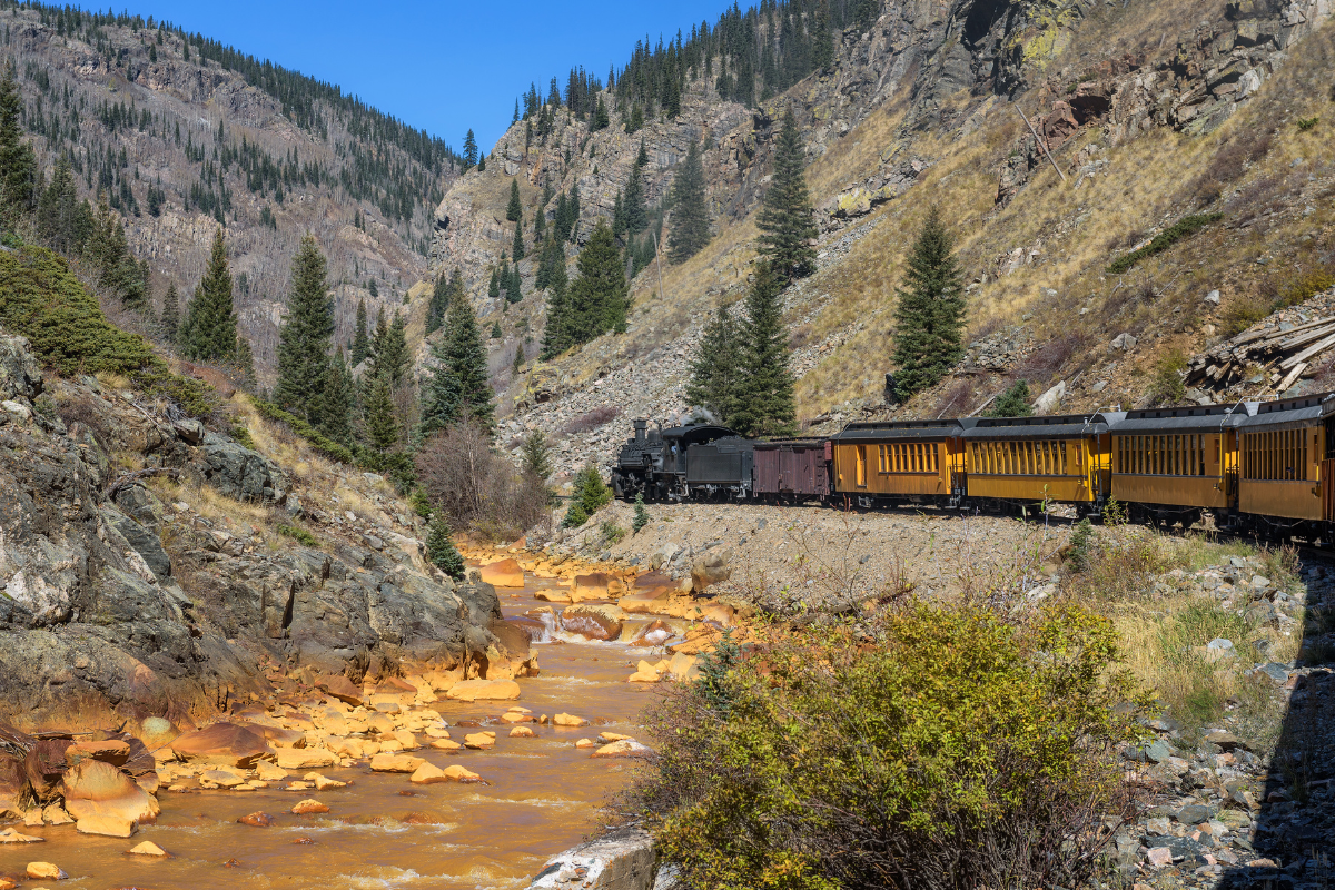 a train traveling down train tracks near a mountain