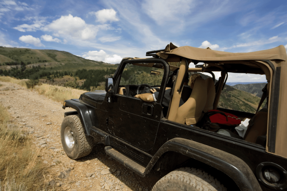 a black jeep driving on a mountain road in the Rocky Mountains