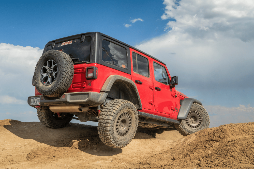 a red jeep on an uneven dirt road